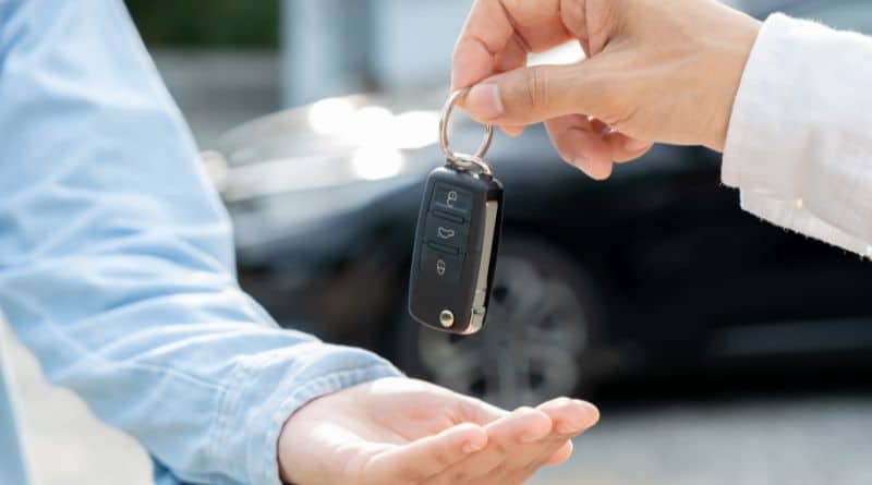 na imagem, uma pessoa entrega uma chave de carro a outra